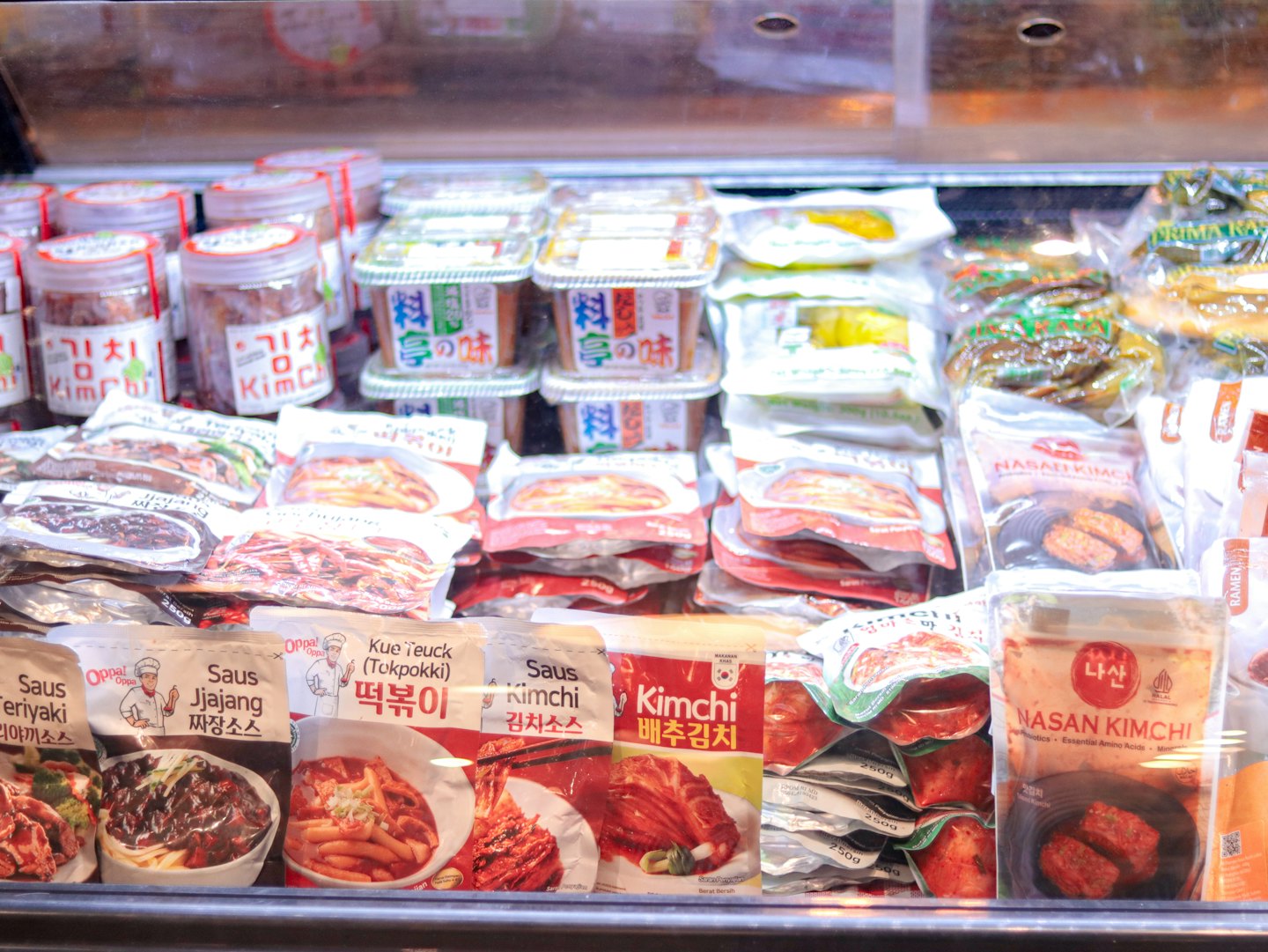 Paketlenmiş Kore yemekleriyle dolu soğutuculu vitrin rafı.